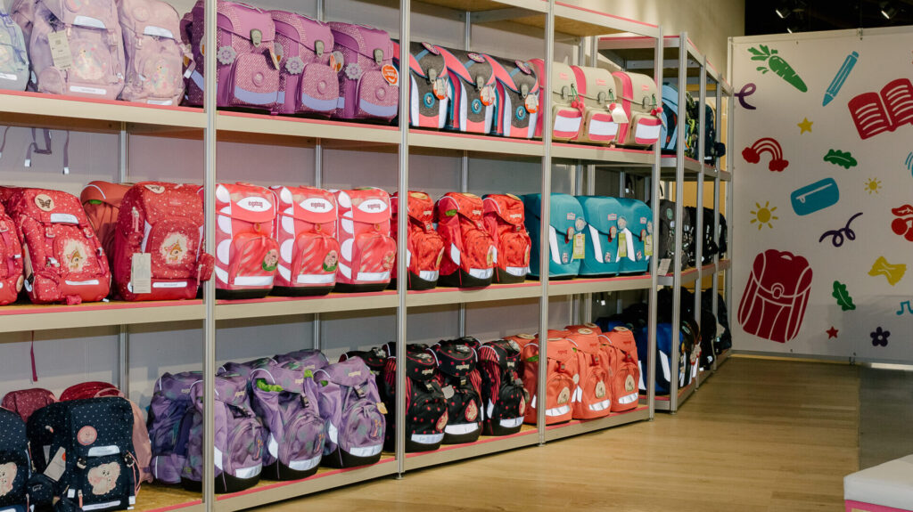 Ein Regal mit pinken und Lilianen Schulranzen in einem Geschäft