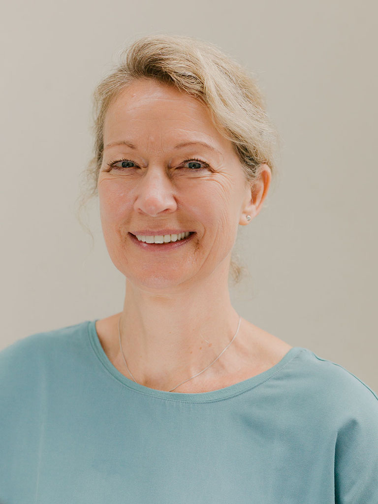 Ein Portrait von einer Frau mit zusammengebundenen blonden Haaren die lächelt