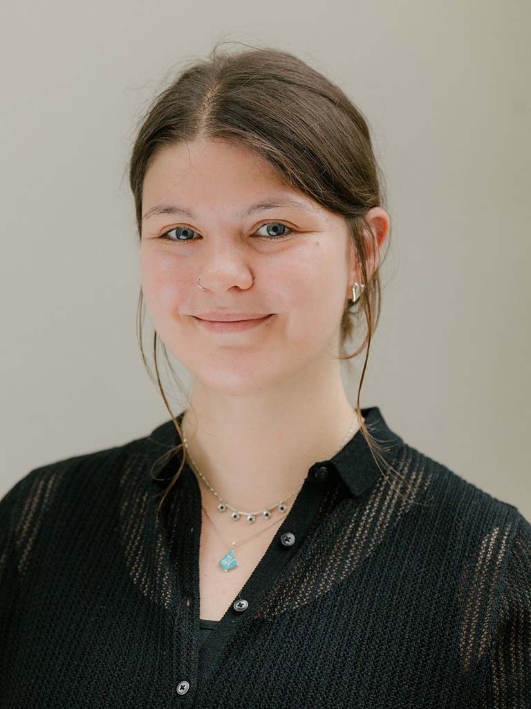 Ein Portrait von einer Frau mit zusammengebundenen braunen Haaren die lächelt