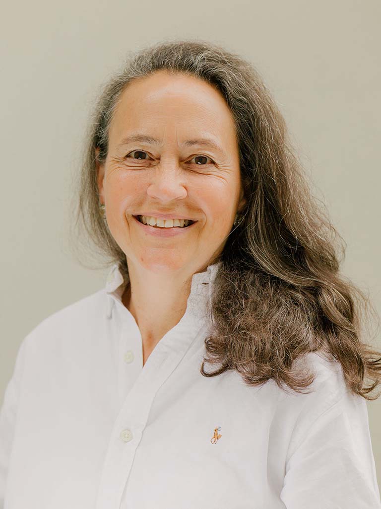 Ein Portrait von einer Frau mit brau-grauen Haaren die lächelt