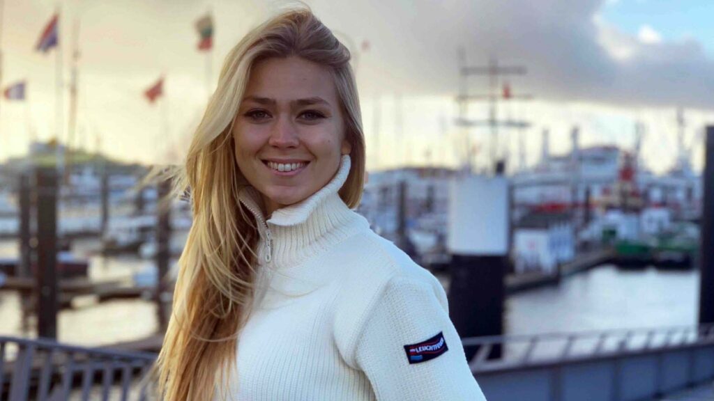 Eine blonde Frau in den Zwanzigern die in die Kamera lächelt.