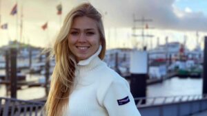 Eine blonde Frau in den Zwanzigern die in die Kamera lächelt.