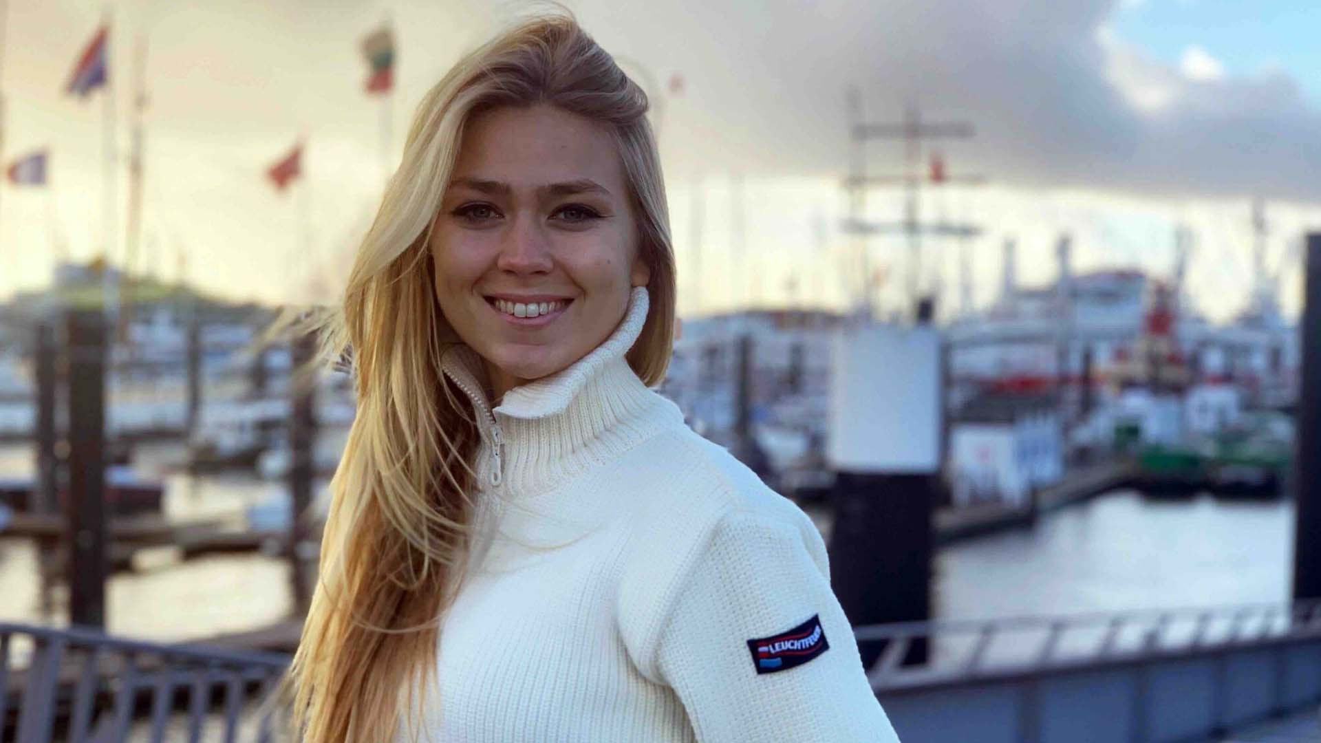 Eine blonde Frau in den Zwanzigern die in die Kamera lächelt.