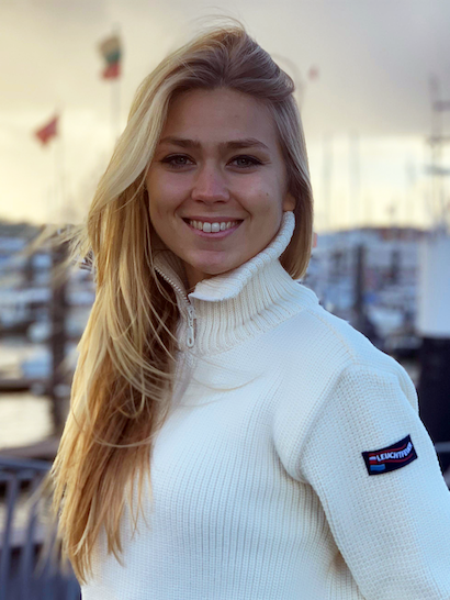 Eine blonde Frau in den Zwanzigern die in die Kamera lächelt.