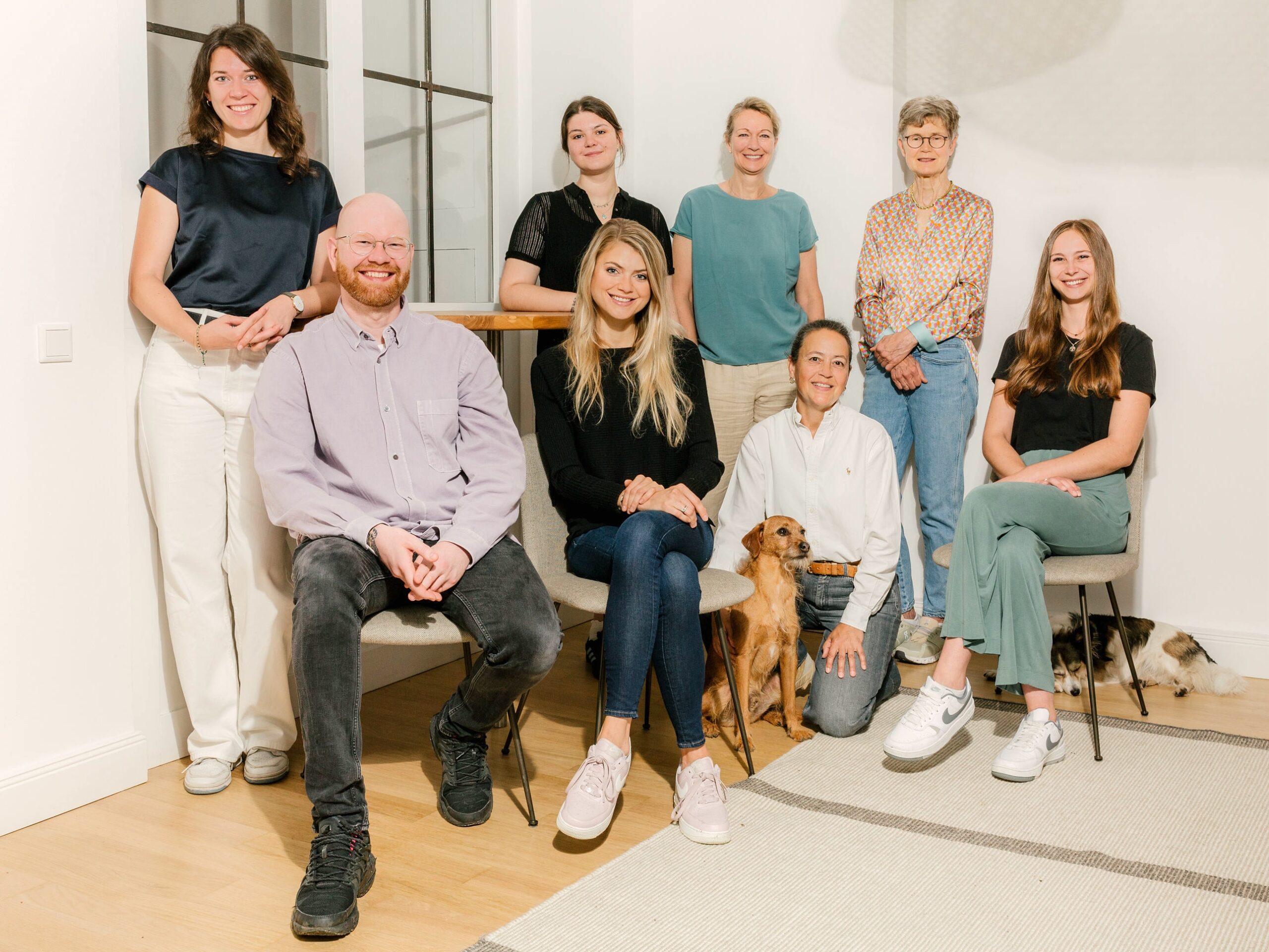 8 Leute und zwei Hunde die für ein Teambild posieren