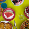 Tisch mit grüner Tischdecke und Tellern mit Wassermelone, Pizza, Beeren